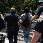 Police escort a handcuffed man across a city street