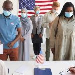 Rust Belt Polls May Be Missing SOMETHING Voters wearing masks stand in line at a polling station