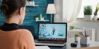Woman on laptop having video call with doctor in home office