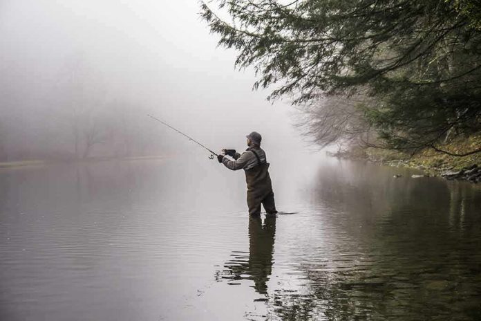 Angler wading in a foggy river casting a fishing rod