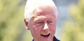 Bill Clinton smiling outdoors in a blue blazer and red shirt