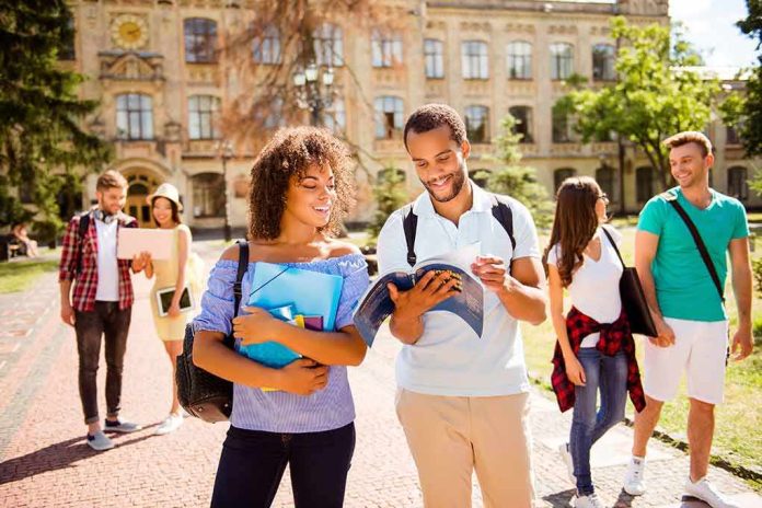shutterstock_684325948 College students walking on campus with books and backpacks